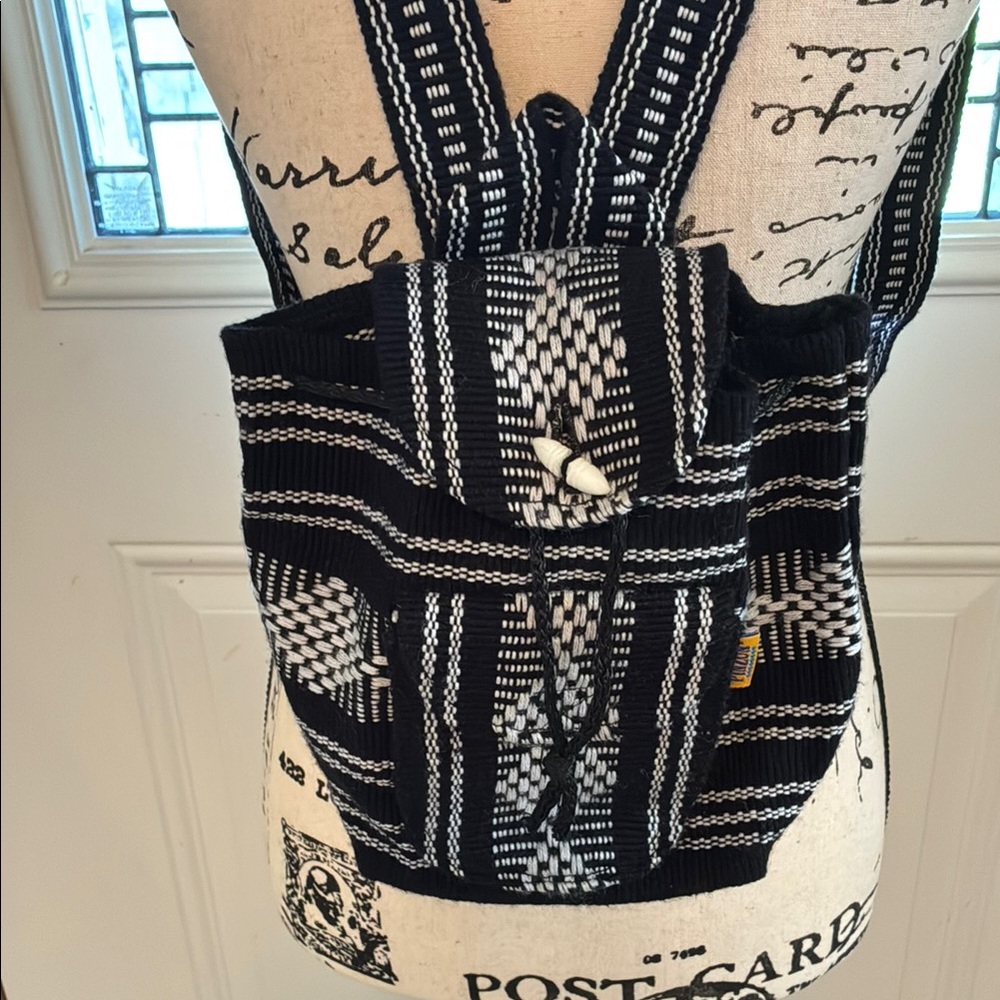 Black & white Pinzon Mini Backpack w/drawstring & button closure. Front pocket